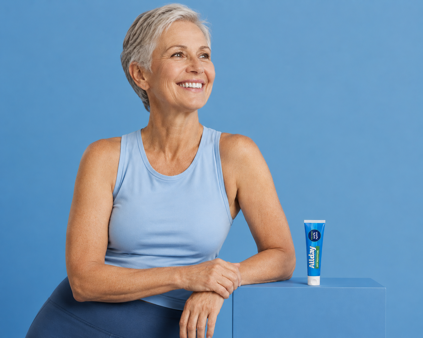 Woman in a blue tank top with a Allday Dry Mouth Gel product tube on a blue background