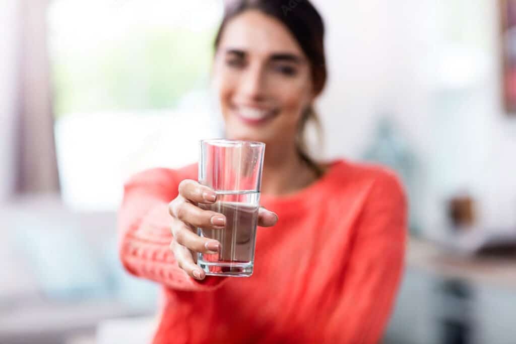 Person holding out a glass of water with a blurred background